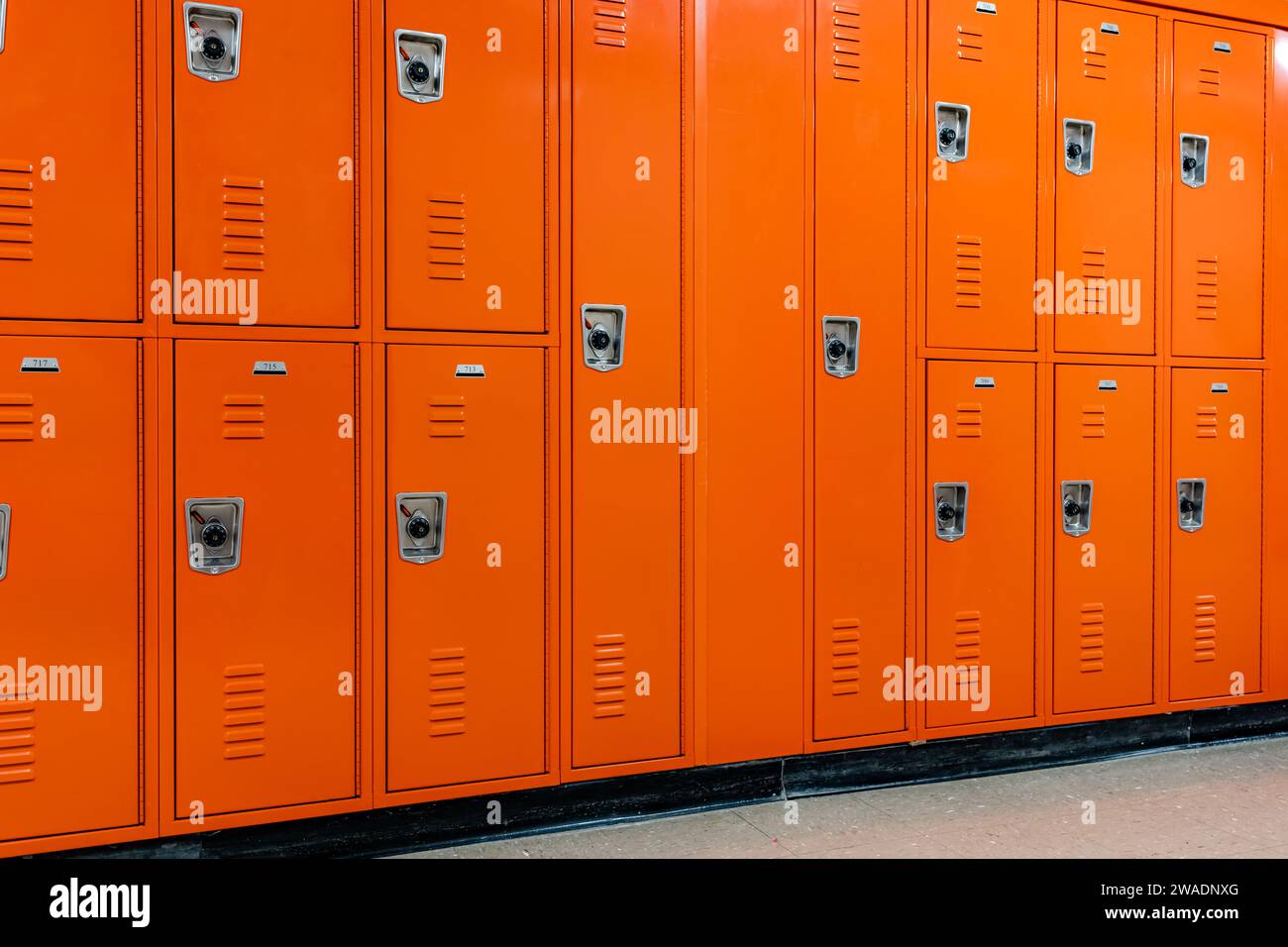 Casiers en métal orange le long d'un couloir indescriptible dans un lycée américain typique. Aucune information identifiable incluse et personne dans le hall. Banque D'Images