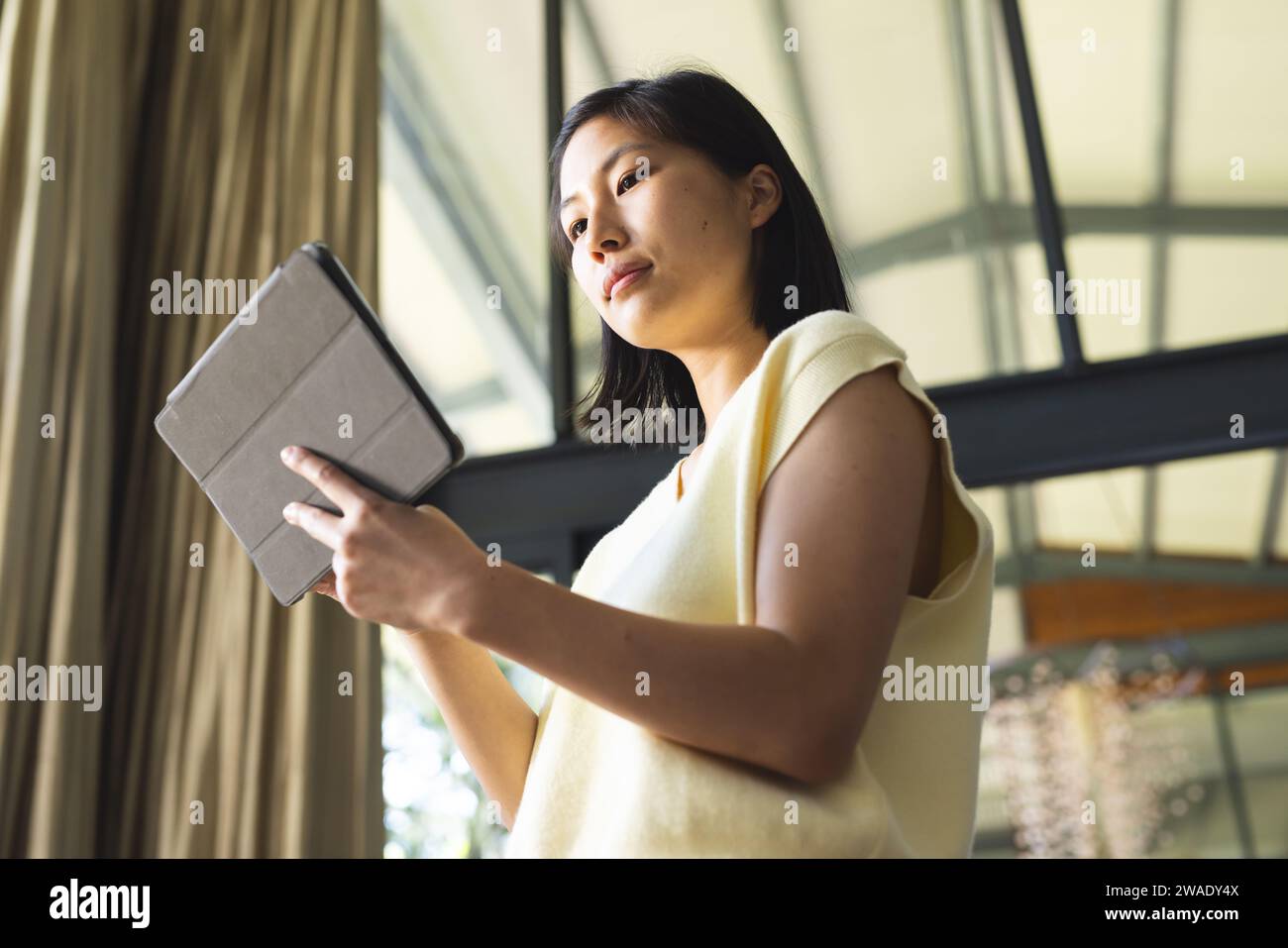 Femme asiatique focalisée avec les cheveux courts en utilisant la tablette à la maison. Vie domestique, technologie et mode de vie, inchangés. Banque D'Images