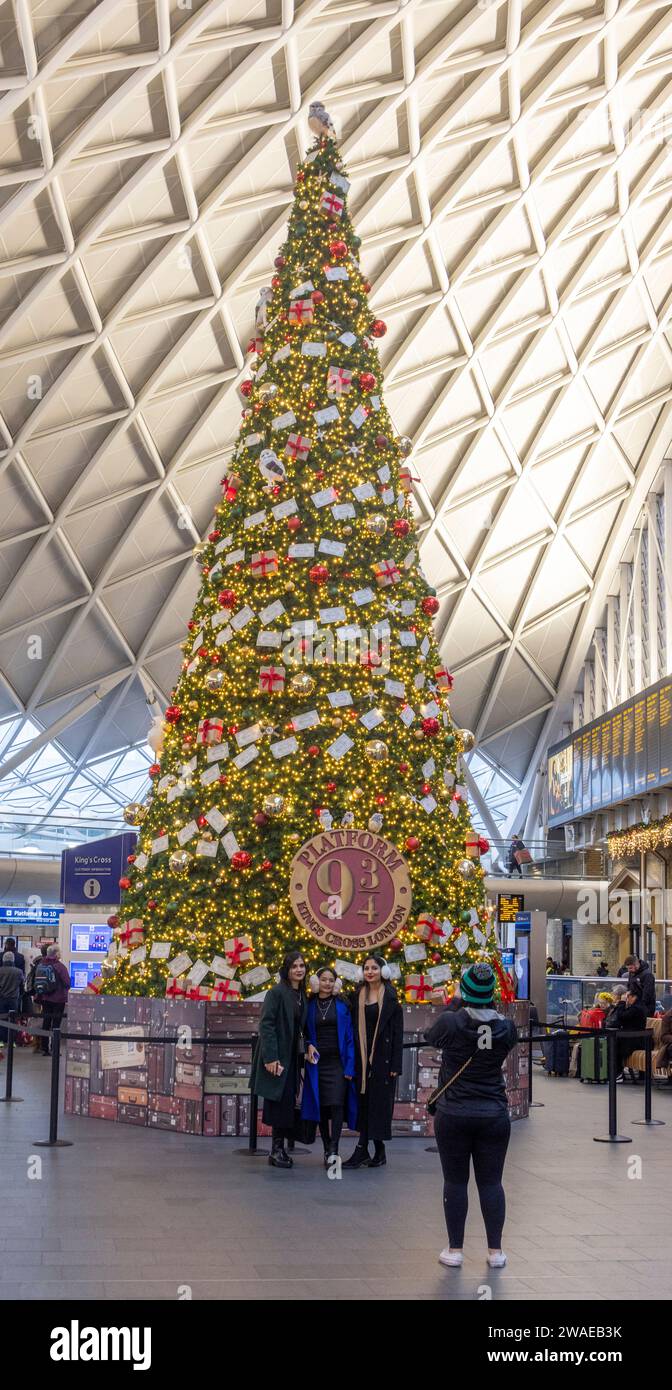 Passagers prenant des photos, arbre de Noël sponsorisé par la boutique Harry Potter au quai 9¾, Kings Cross Station, Londres, Royaume-Uni Banque D'Images