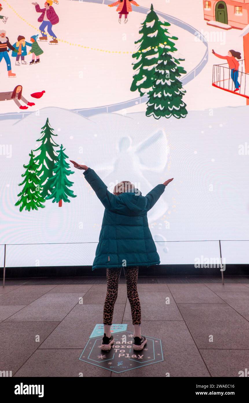 Fille faisant des anges de neige dans l'affichage interactif, The Now Building, Londres, Royaume-Uni Banque D'Images