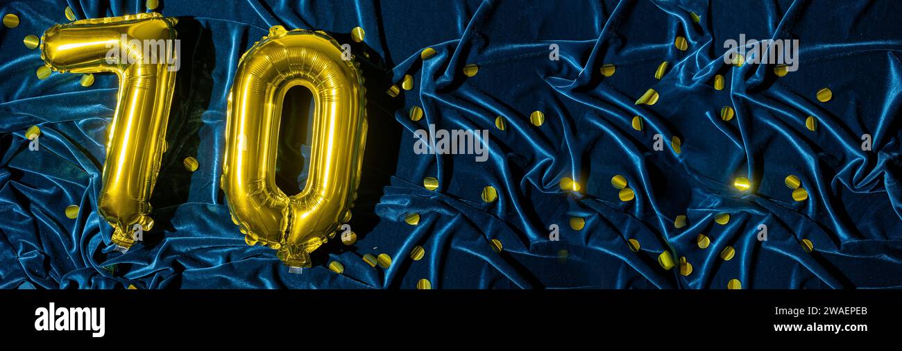 Ballon en feuille d'or numéro 70 sur fond de décoration de velours bleu. Carte de voeux d'anniversaire, inscription soixante-dix. Événement anniversaire. Bannière. Banque D'Images