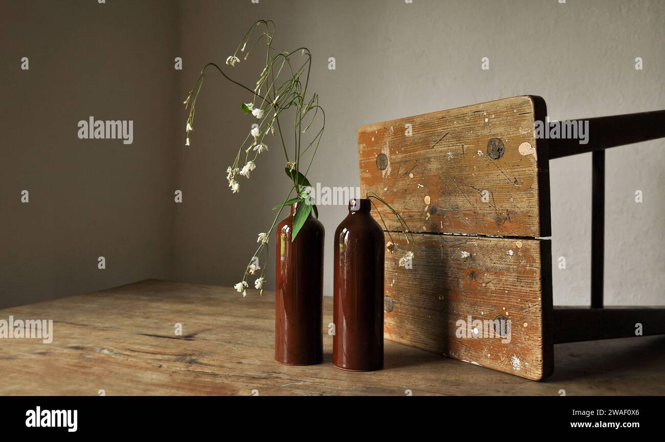Une composition artistique de détails intérieurs rustiques. Fragments de vieux meubles en bois minable. Bouteilles d'argile, plante fanée trempée. Durabilité Banque D'Images