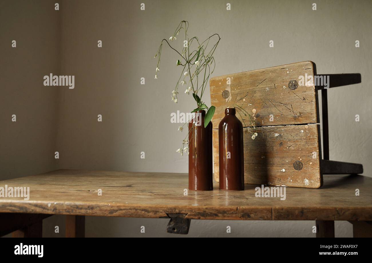 Une composition artistique de détails intérieurs rustiques. Fragments de vieux meubles en bois minable. Bouteilles d'argile, plante fanée trempée. Durabilité Banque D'Images