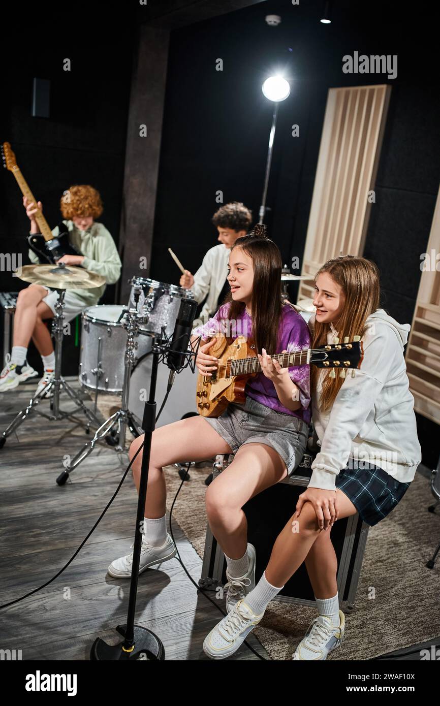 concentrez-vous sur les adolescentes qui chantent à la guitare pendant que leurs amis flous jouent des instruments Banque D'Images