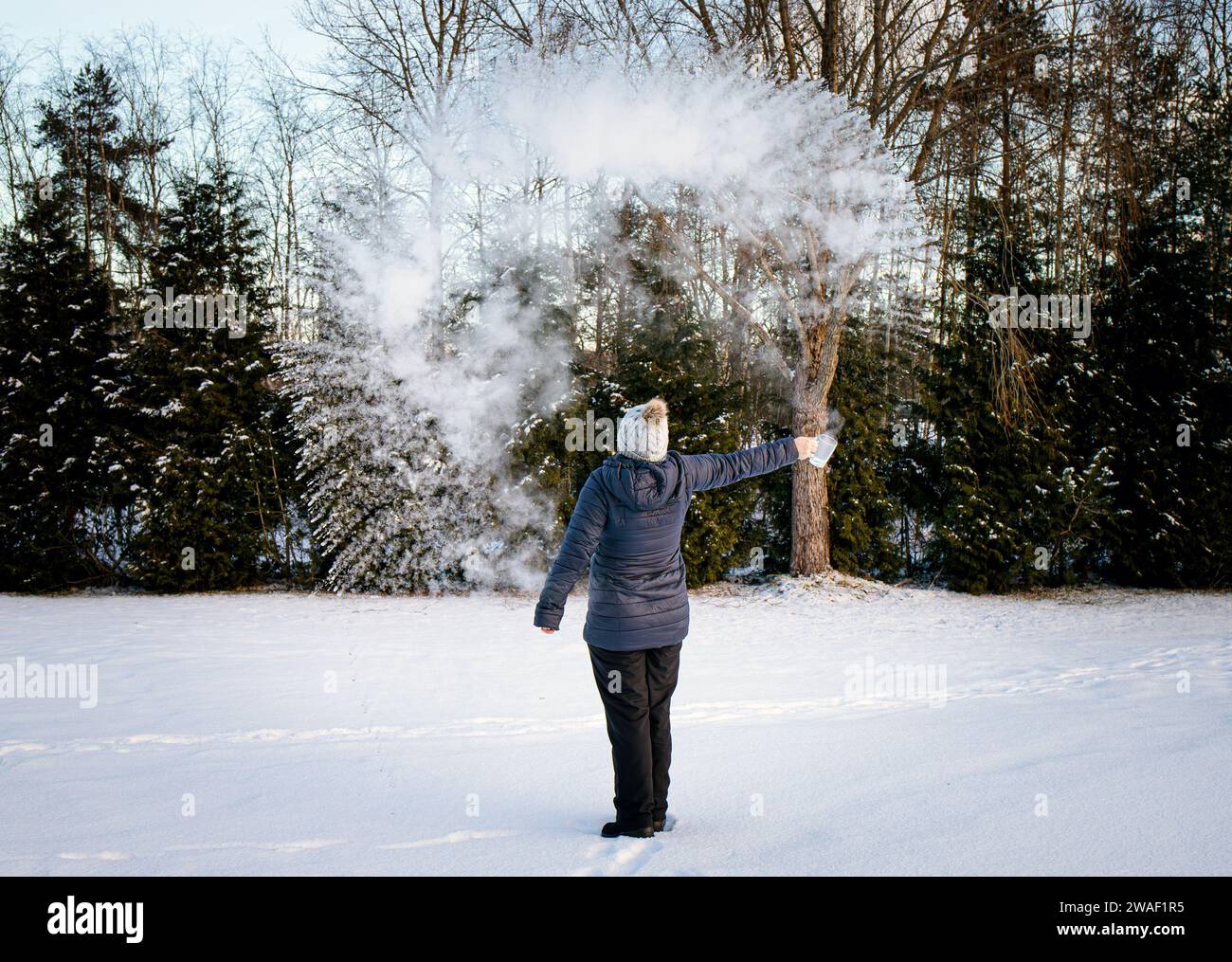 Expérience de lancer de l'eau bouillante dans l'air froid glacial l'eau s'évapore et se condense rapidement, permettant à un nuage de se former. Science amusante. Banque D'Images