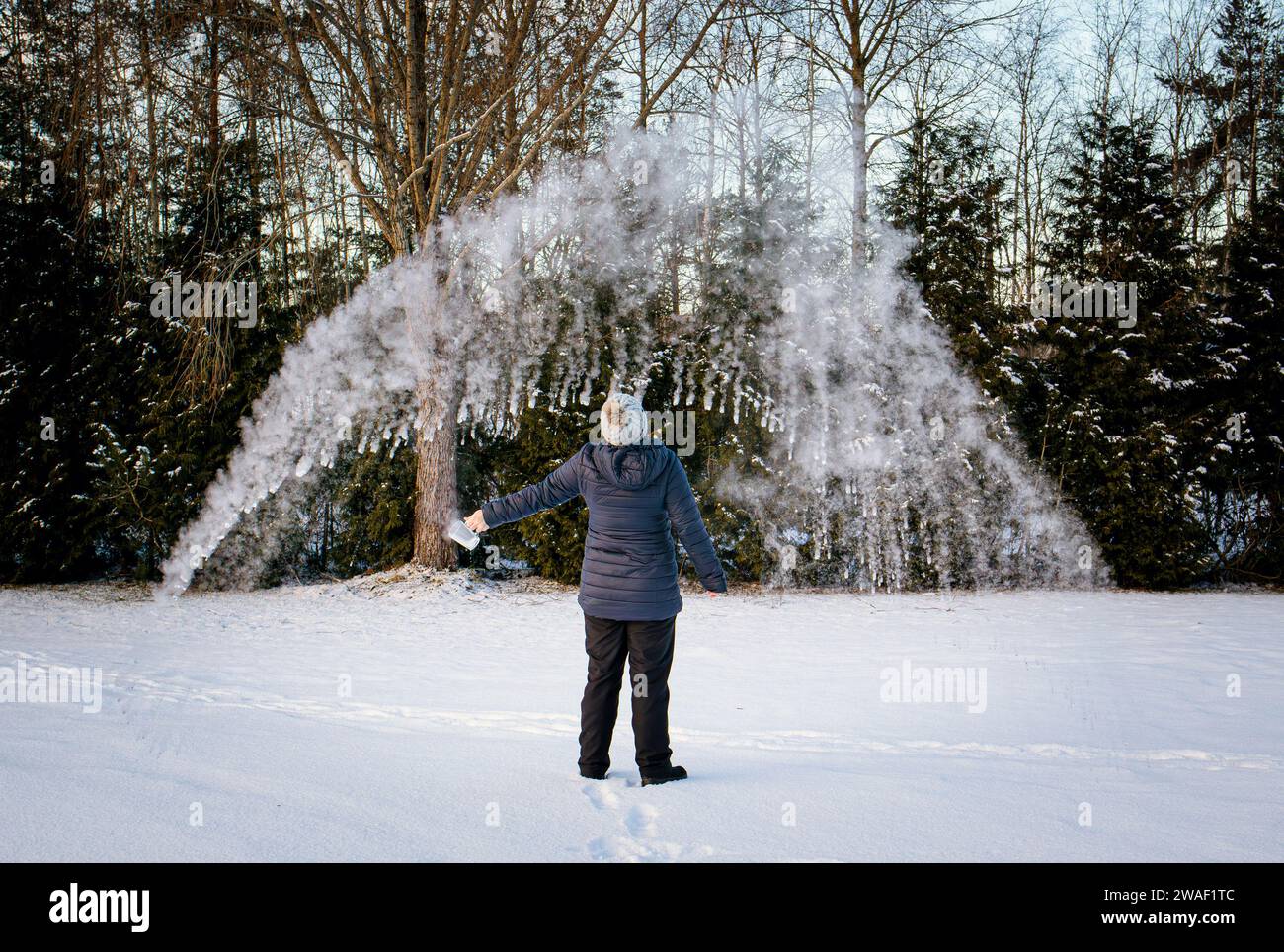 Expérience de lancer de l'eau bouillante dans l'air froid glacial l'eau s'évapore et se condense rapidement, permettant à un nuage de se former. Science amusante. Banque D'Images