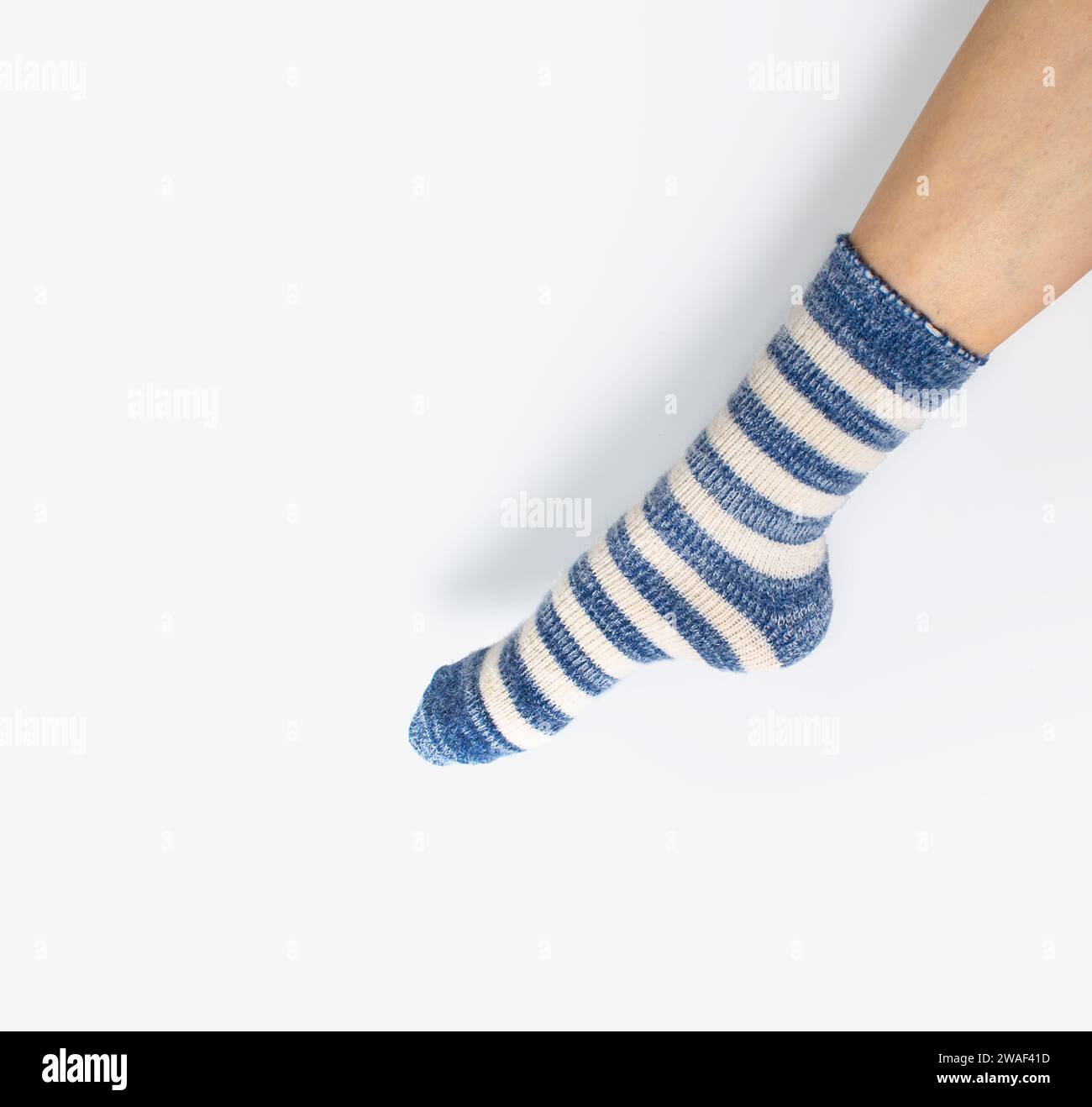 Vue latérale de la jambe en chaussette de deux couleurs alternant bleu et blanc. Fond blanc, isolé Banque D'Images