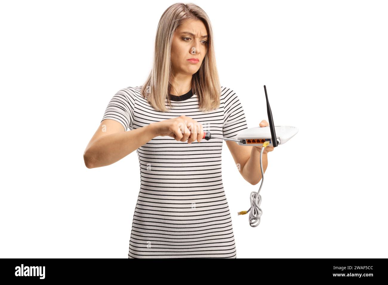 Jeune femme confuse fixant un routeur isolé sur fond blanc Banque D'Images Jeune femme confuse fixant un routeur isolé sur fond blanc Banque D'Images