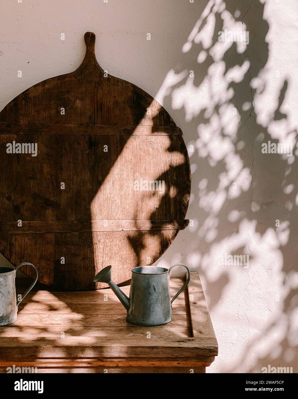 Une planche en bois de style vintage et un arrosoir en métal sur une table rustique dans le jardin Banque D'Images