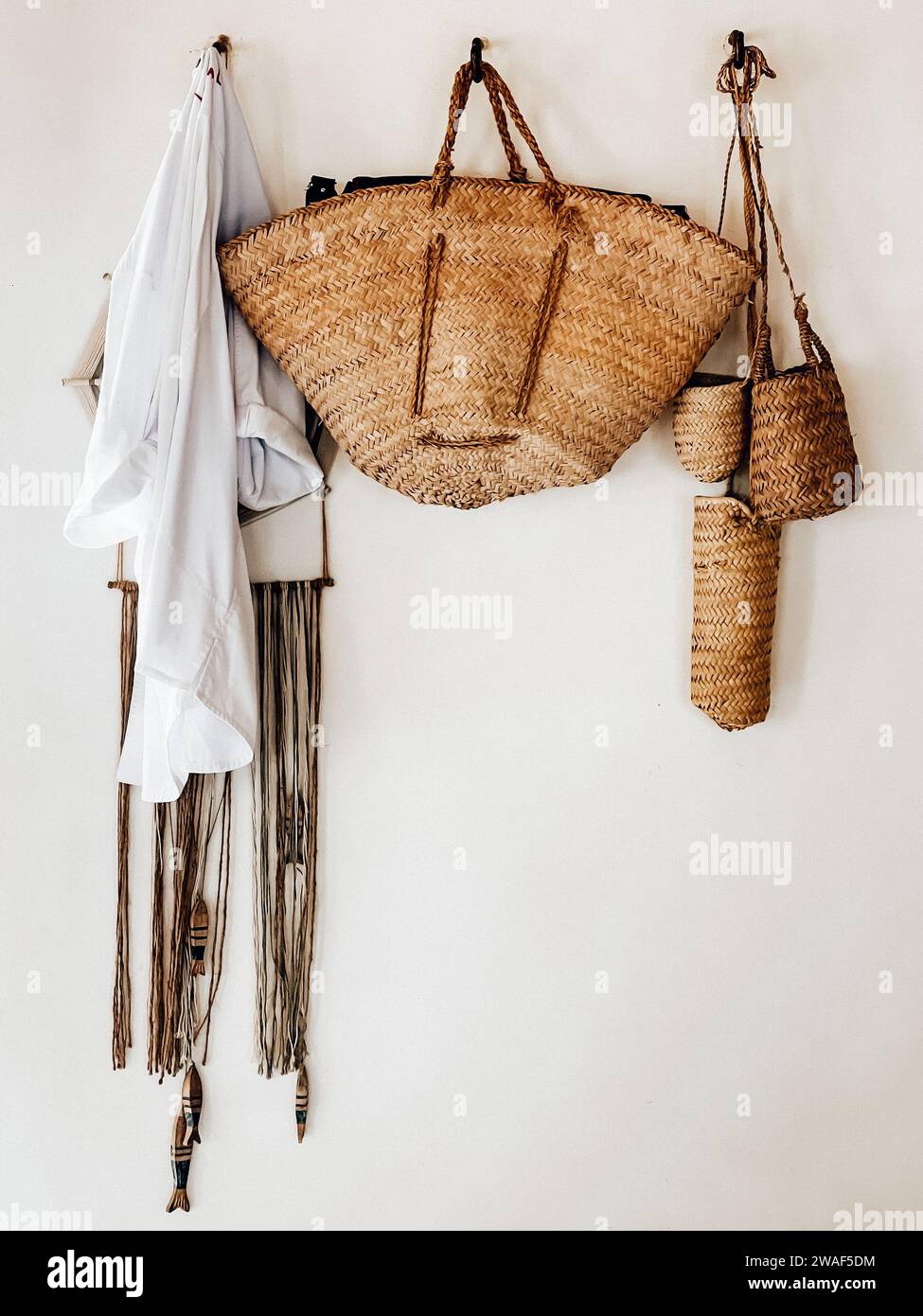Une sélection de sacs en rotin accrochés au mur. Cala Jondal, Ibiza, Espagne Banque D'Images