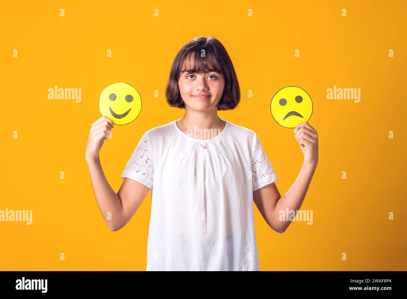 Fille tient des émoticônes tristes et heureux dans les mains. Santé mentale, psychologie et concepts émotionnels de l'enfant Banque D'Images