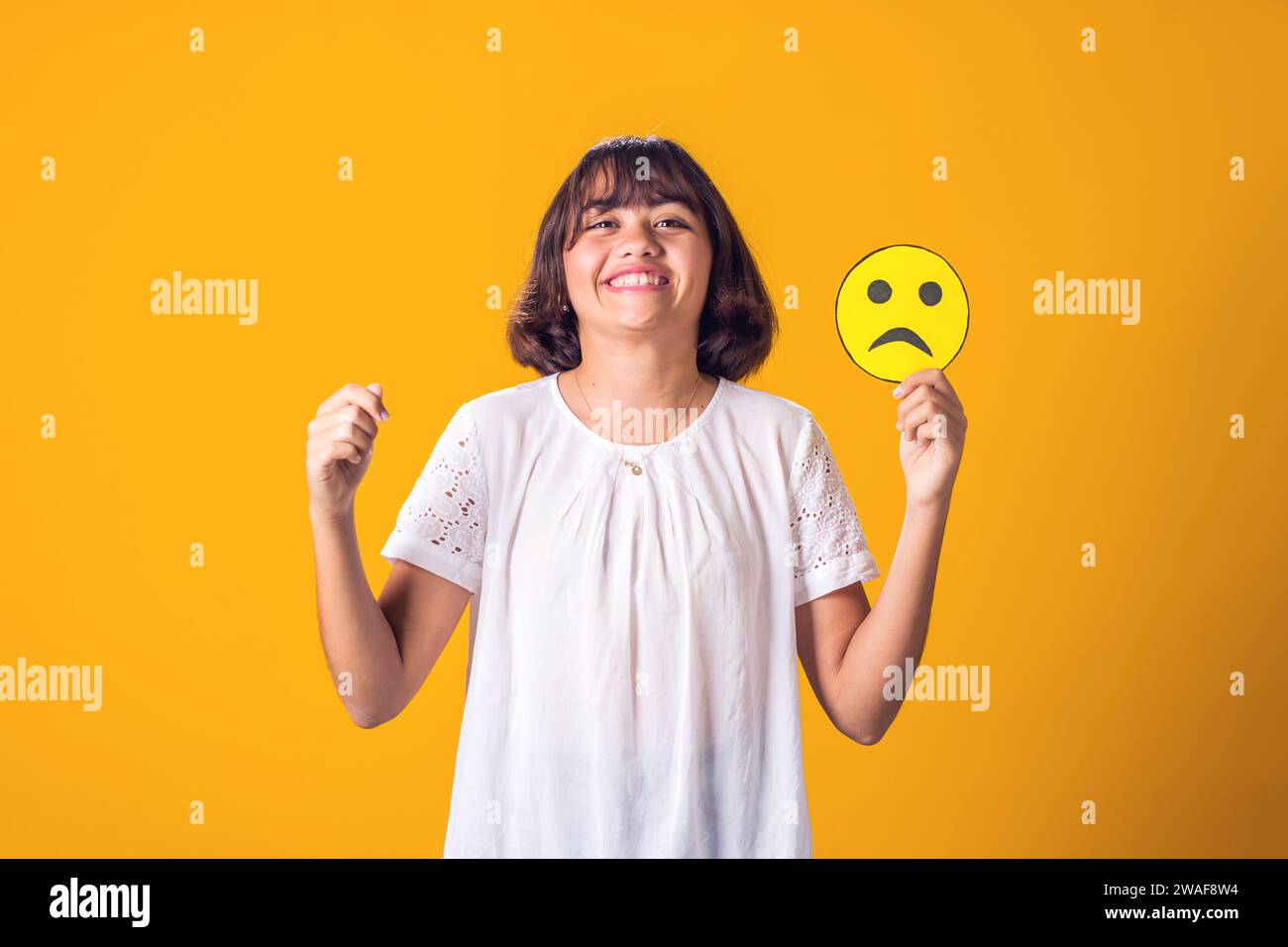 Fille sourire et tient une émoticône triste. Santé mentale, psychologie et concepts émotionnels de l'enfant Banque D'Images