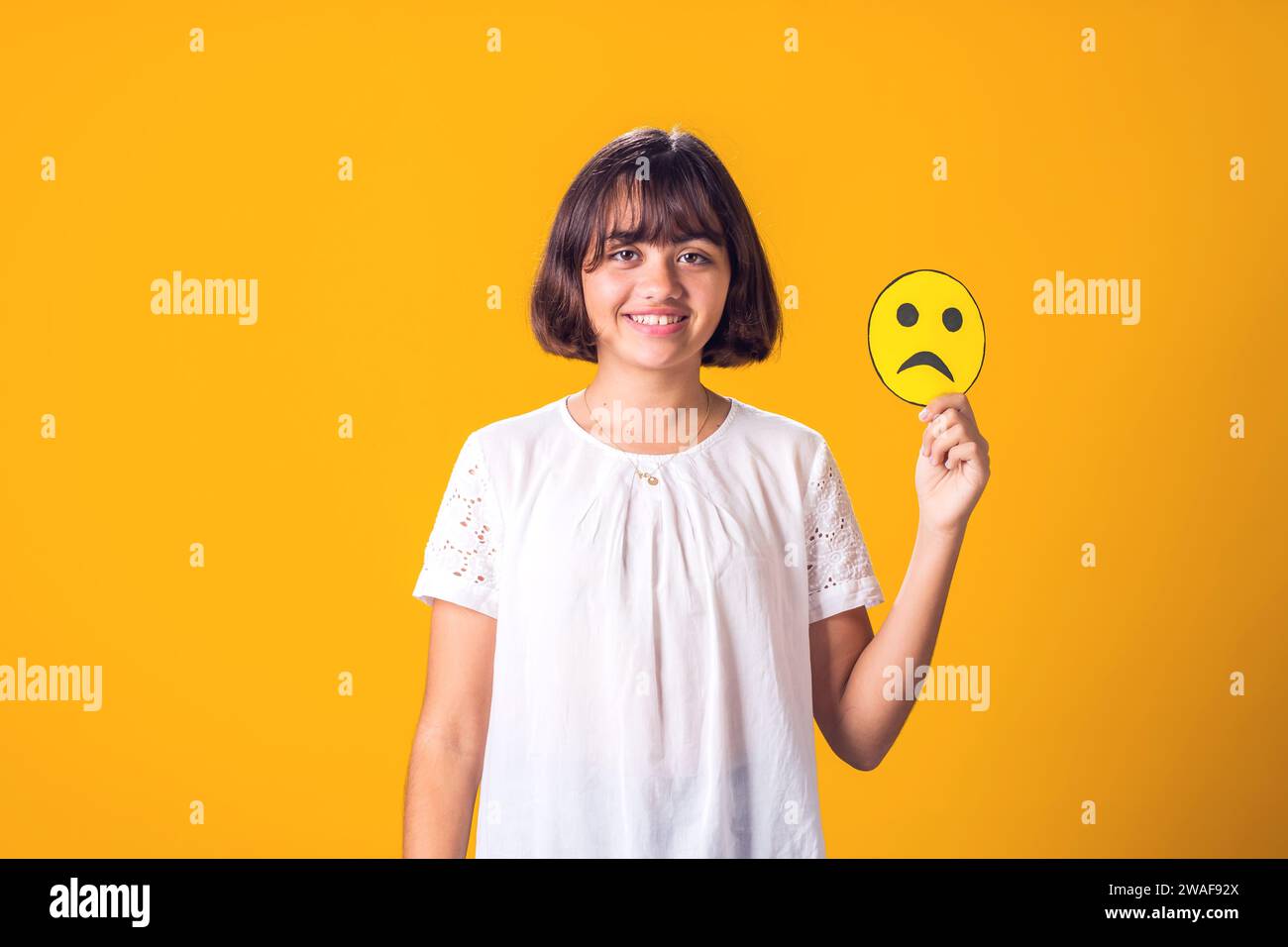 Fille sourire et tient une émoticône triste. Santé mentale, psychologie et concepts émotionnels de l'enfant Banque D'Images