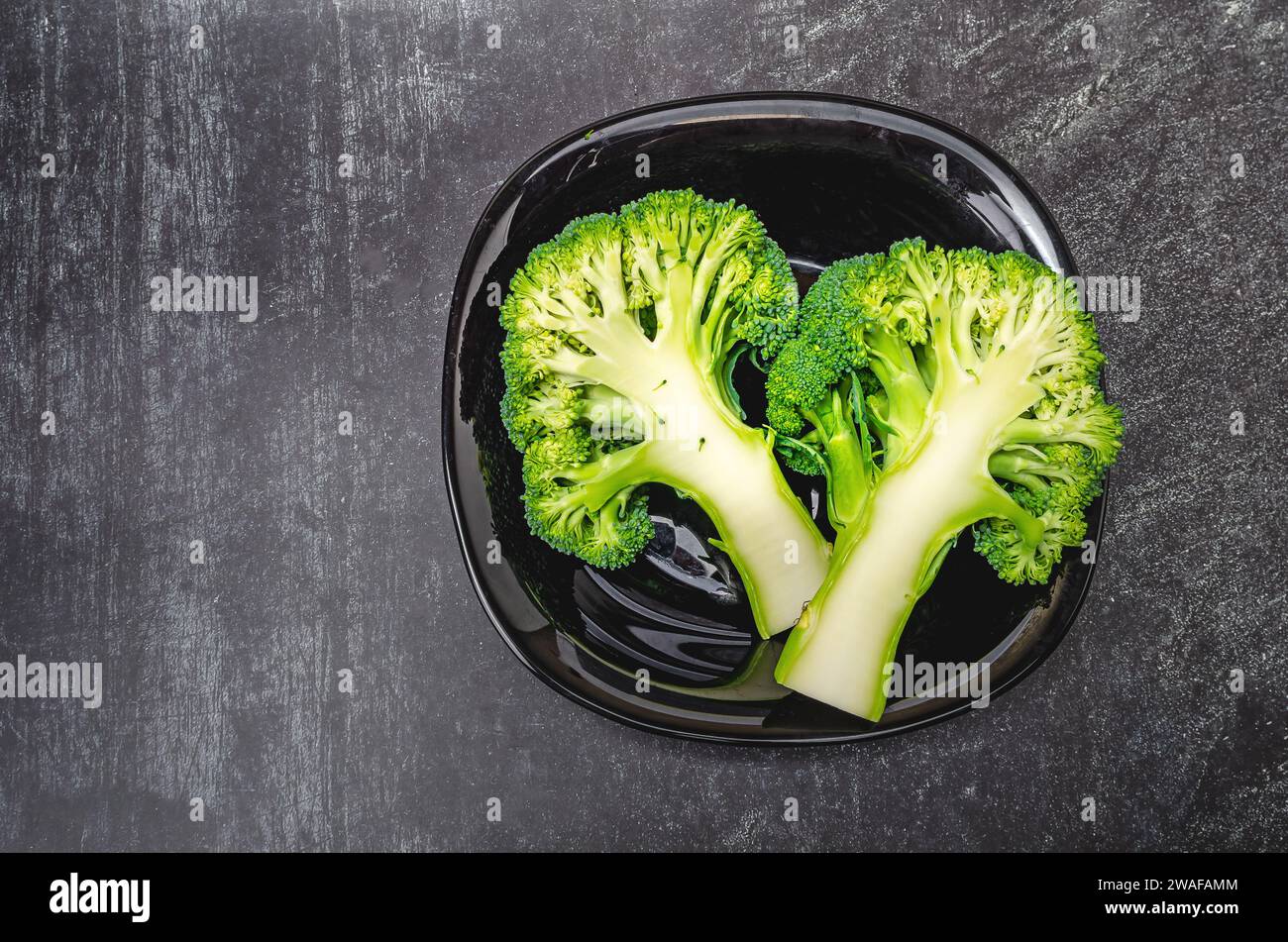 Deux moitiés de brocoli vert frais dans un bol noir sur fond gris. Une alimentation saine. Banque D'Images