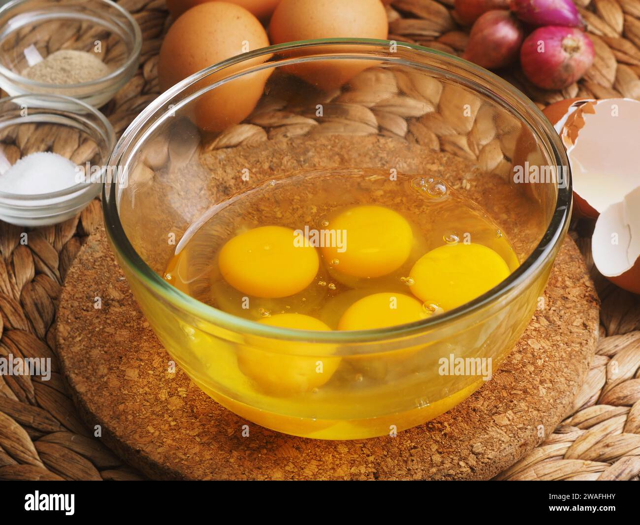 Préparation de la confection de telur dadar, omelette indonésienne, avec des oeufs d'ingrédient dans le bol en verre, comme un fond d'oignon rouge, et le sel et le papper Banque D'Images