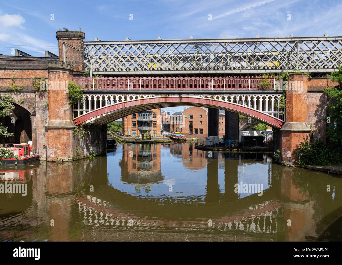 Un train traversant un viaduc ferroviaire victorien sur le canal Bridgewater, Manchester. Pont ferroviaire victorien reflétant dans le canal. Banque D'Images