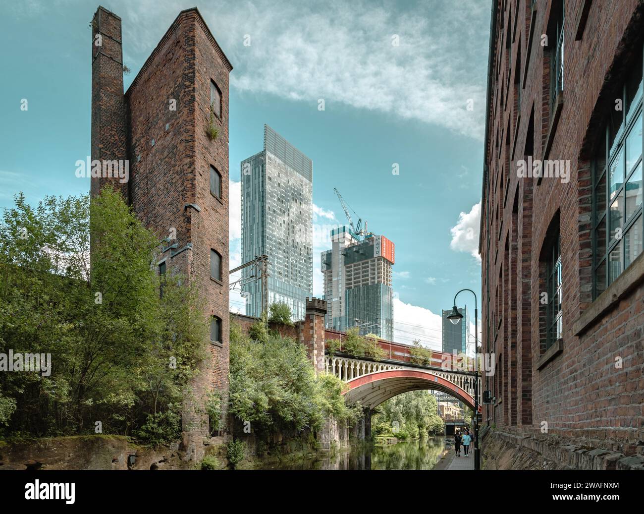 Charme vintage et horizon urbain, pont victorien et patrimoine industriel contrastent avec les gratte-ciel modernes le long du canal Rochdale. Banque D'Images
