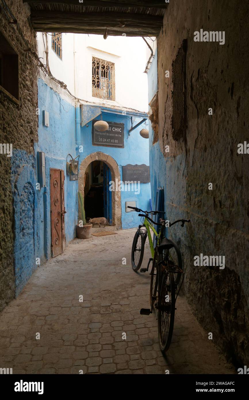 Vélos dans une rue étroite avec des bâtiments bleus dans la ville d'Essaouira, Maroc. 4 janvier 2024 Banque D'Images