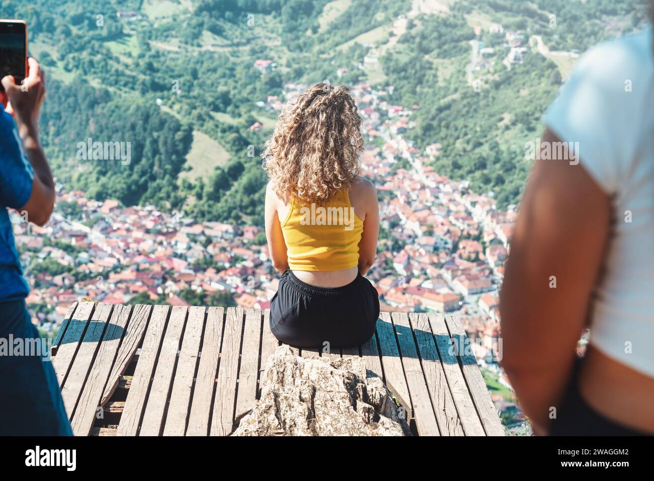 Vue arrière avec une jeune fille blonde non identifiable profitant de la vue depuis la pointe du belvédère sur le mont Tampa sur la ville de Brasov, Roumanie. Banque D'Images