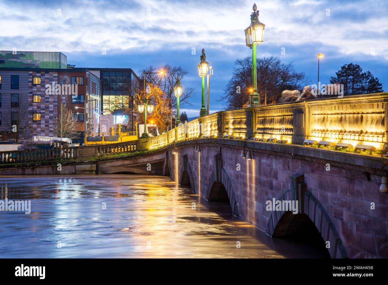 Au coucher du soleil, après un temps orageux et humide, d'importants torrents d'eau de pluie passant sous le pont historique lluminé, le long de la Severn, après s'être versés Banque D'Images