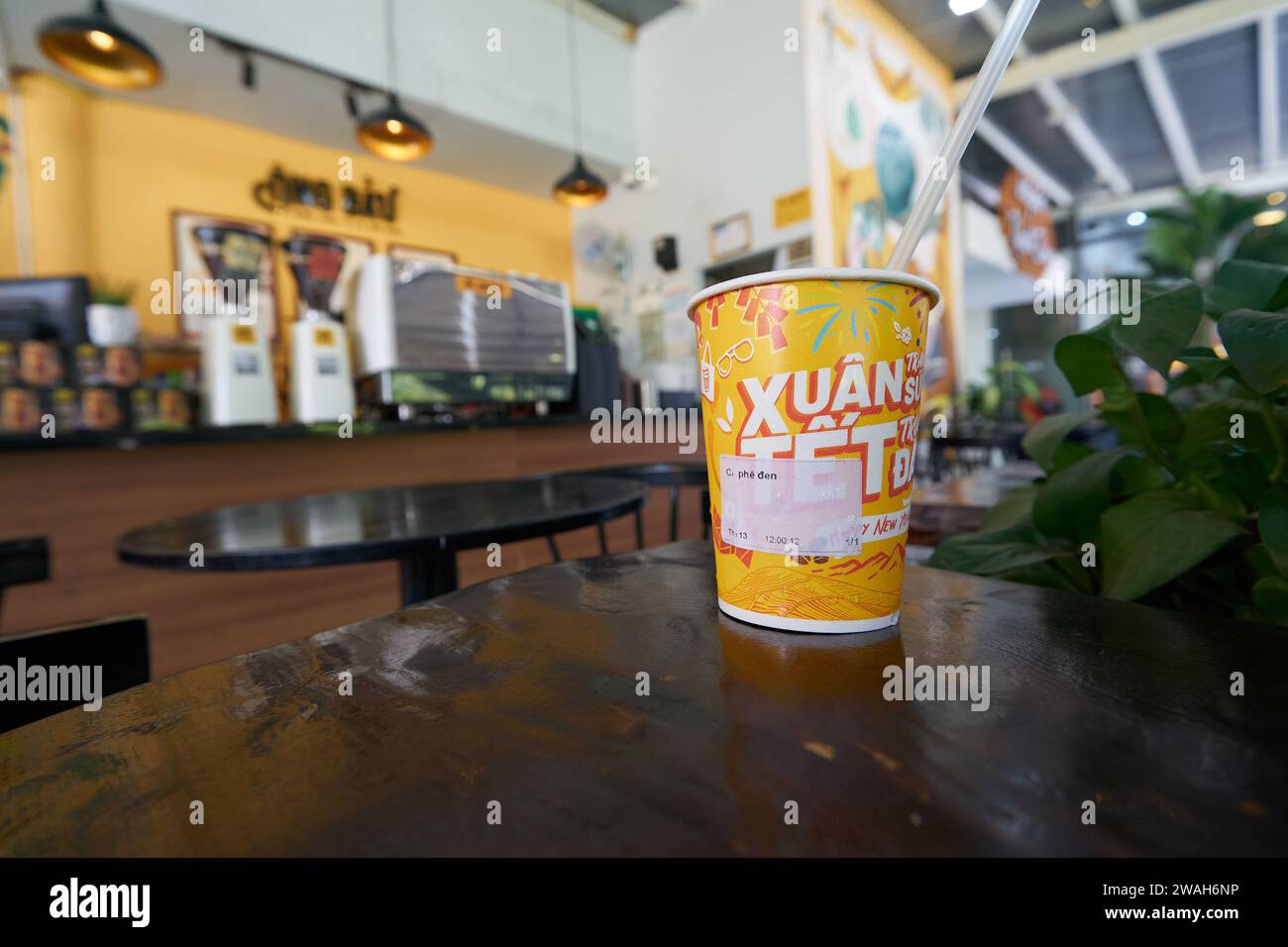 HO CHI MINH VILLE, VIETNAM - 26 MARS 2023 : gros plan d'une tasse en papier avec du café glacé servi sur une table au ONG Bau Coffee à Ho Chi Minh ville. Banque D'Images