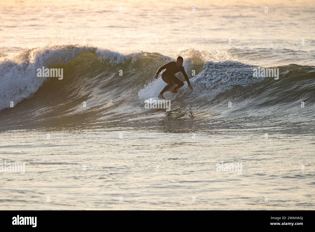Surfer en action au coucher du soleil. Plage de Furadouro, Ovar - Portugal. Banque D'Images