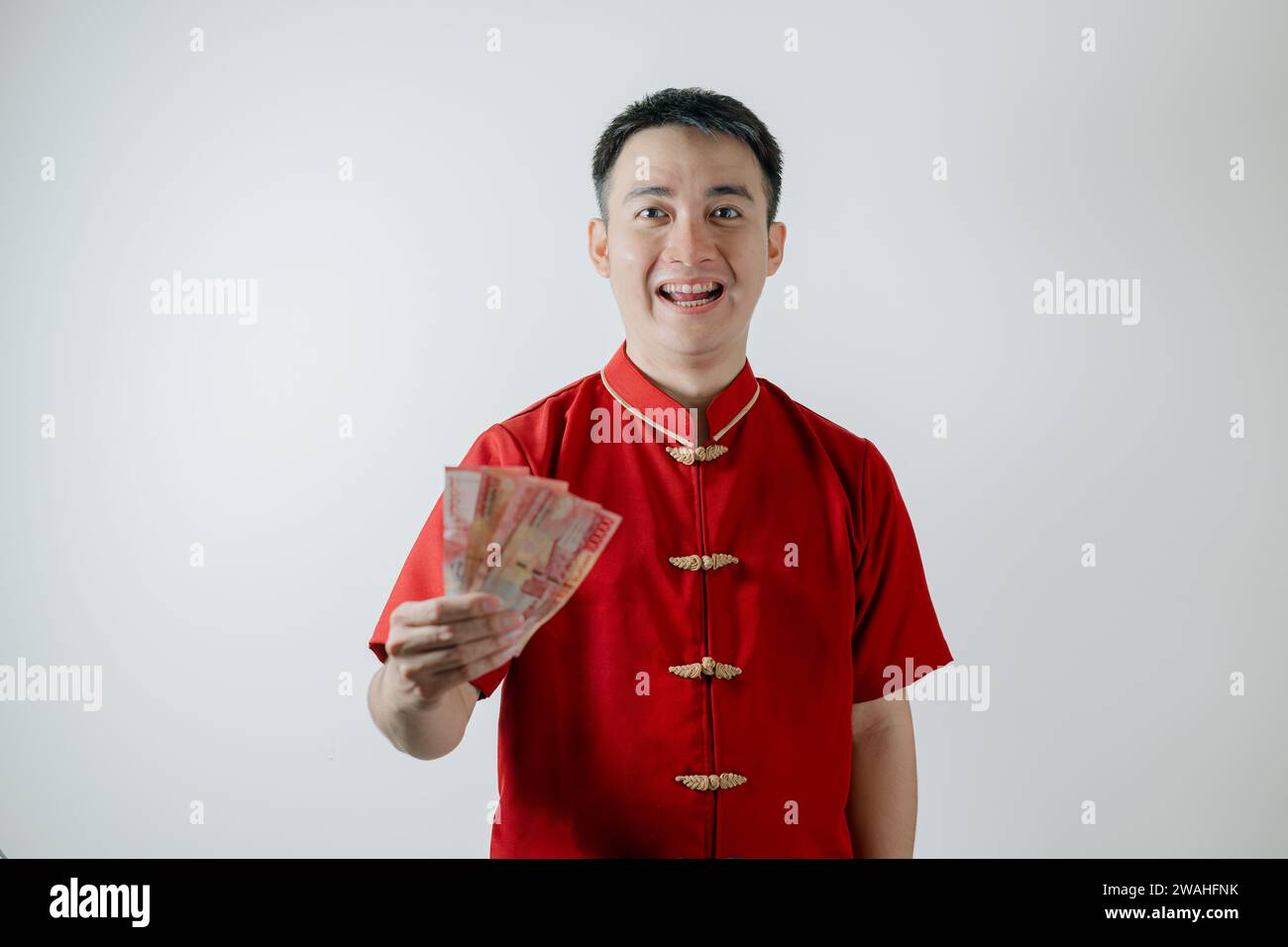 Sourire visage de l'homme asiatique portant Cheongsam ou tissu traditionnel chinois tient des sommes d'argent et regarde la caméra sur fond blanc Banque D'Images