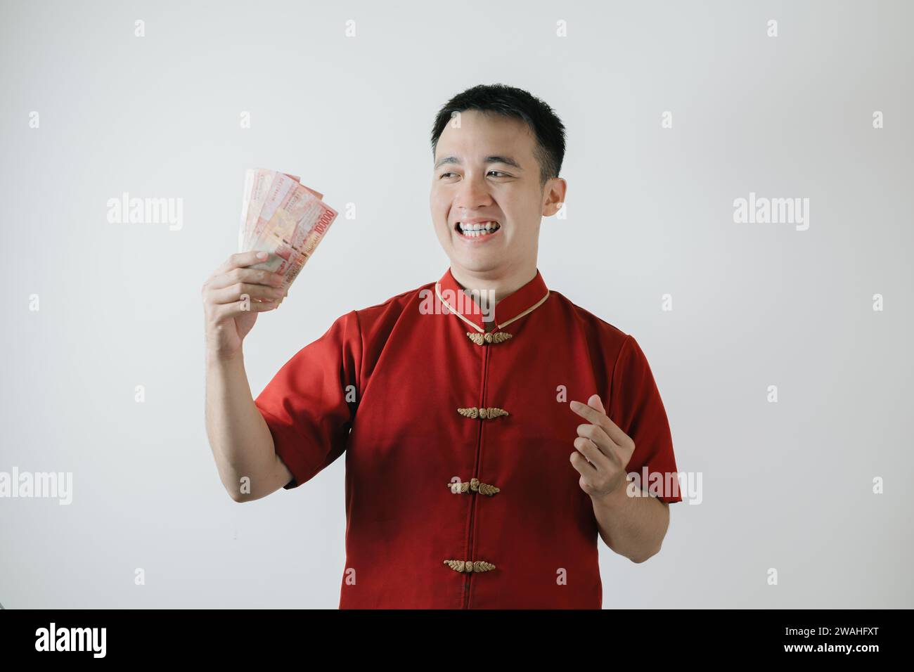 Sourire visage expression de l'homme asiatique portant Cheongsam ou tissu traditionnel chinois tout en tenant des montants d'argent sur fond blanc Banque D'Images