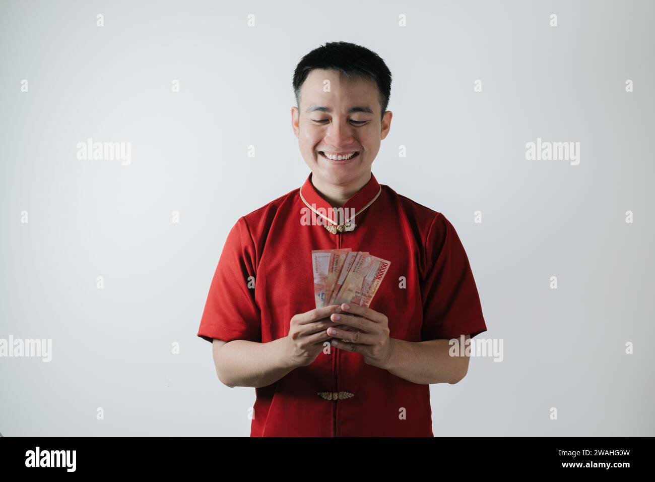 Sourire visage de l'homme asiatique portant Cheongsam ou tissu traditionnel chinois tout en tenant des montants d'argent sur fond blanc Banque D'Images