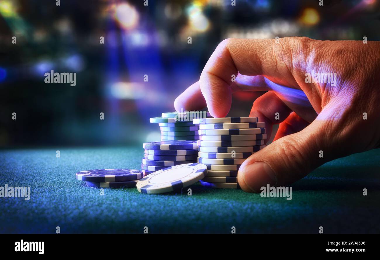 Jetons de jeu de pari de main sur le tapis de feutre avec salle de jeu en arrière-plan. Vue avant. Banque D'Images