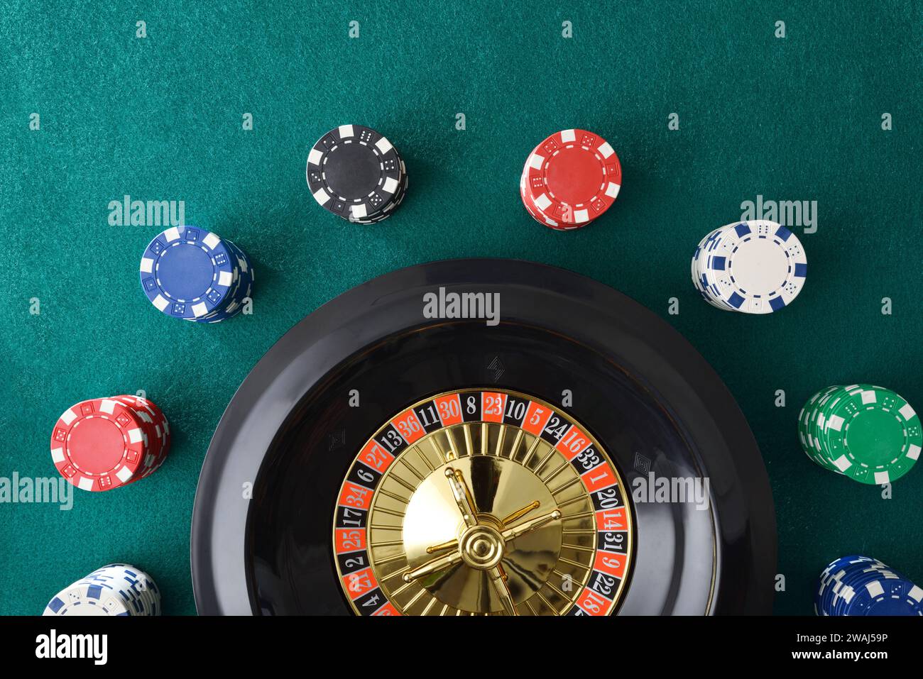 Roulette de casino isolé sur tapis de feutre vert avec des jetons colorés pour parier autour. Vue de dessus. Banque D'Images