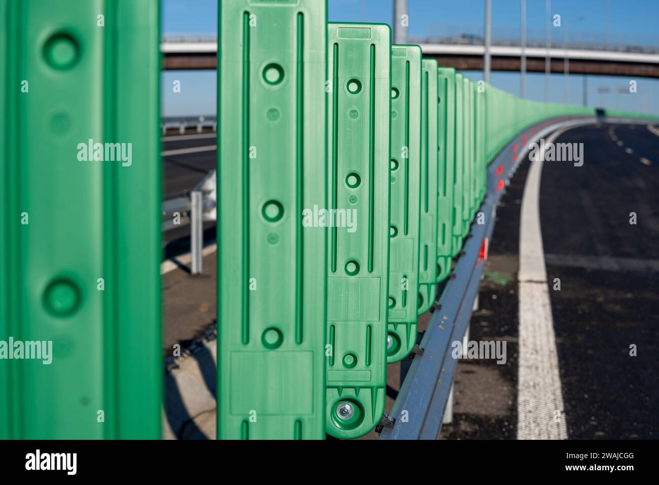 Les poteaux de clôture métalliques verts bordant le côté d'une route asphaltée Banque D'Images