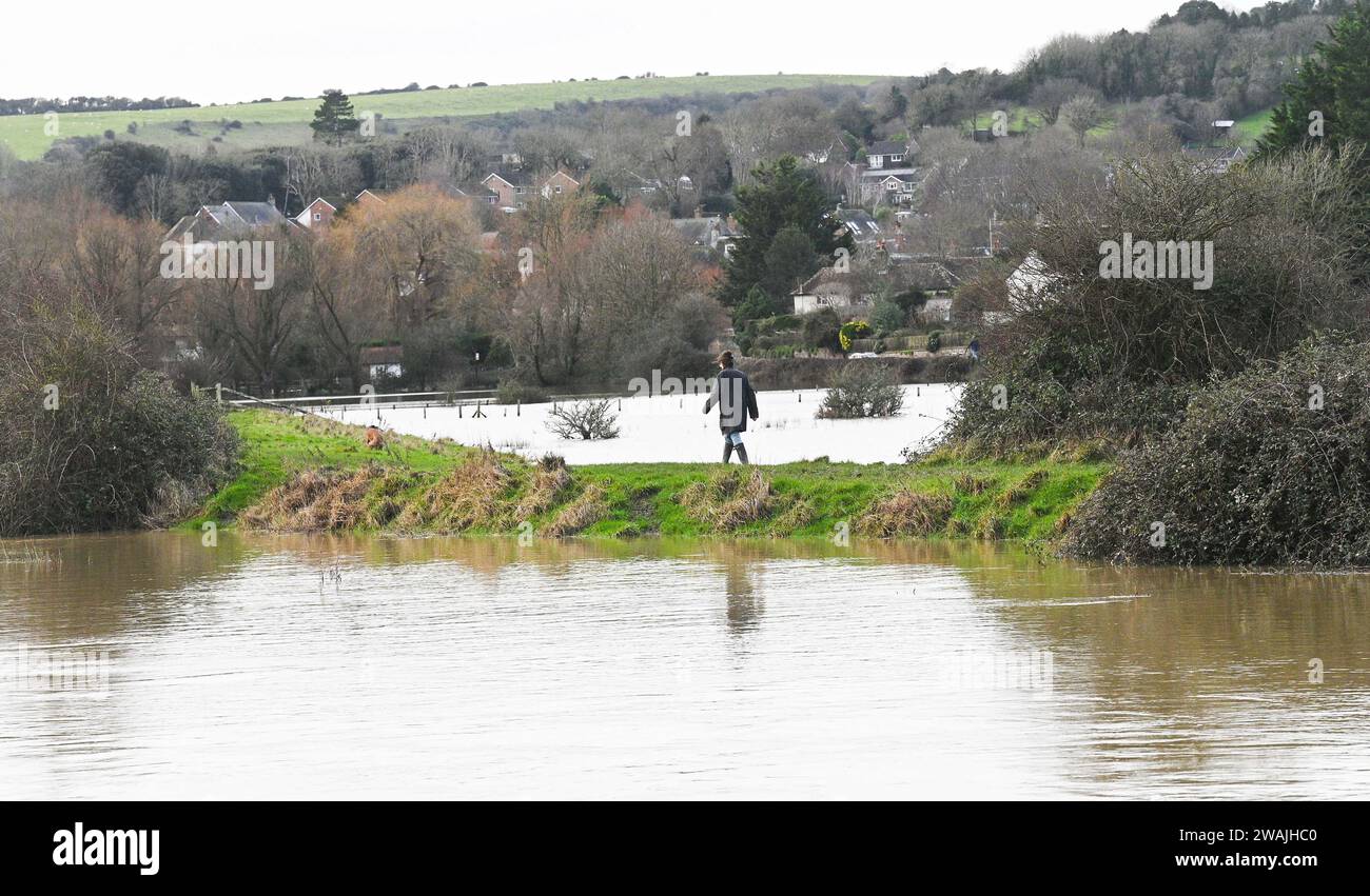 Alfriston, Sussex Royaume-Uni 5 janvier 2024 - Un marcheur trouve un chemin entre les inondations par la rivière Cuckmere qui a éclaté ses rives près d'Alfriston après une autre nuit de fortes pluies avec plus de 300 avertissements d'inondation et de météo émis dans tout le pays : crédit Simon Dack / Alamy Live News Banque D'Images