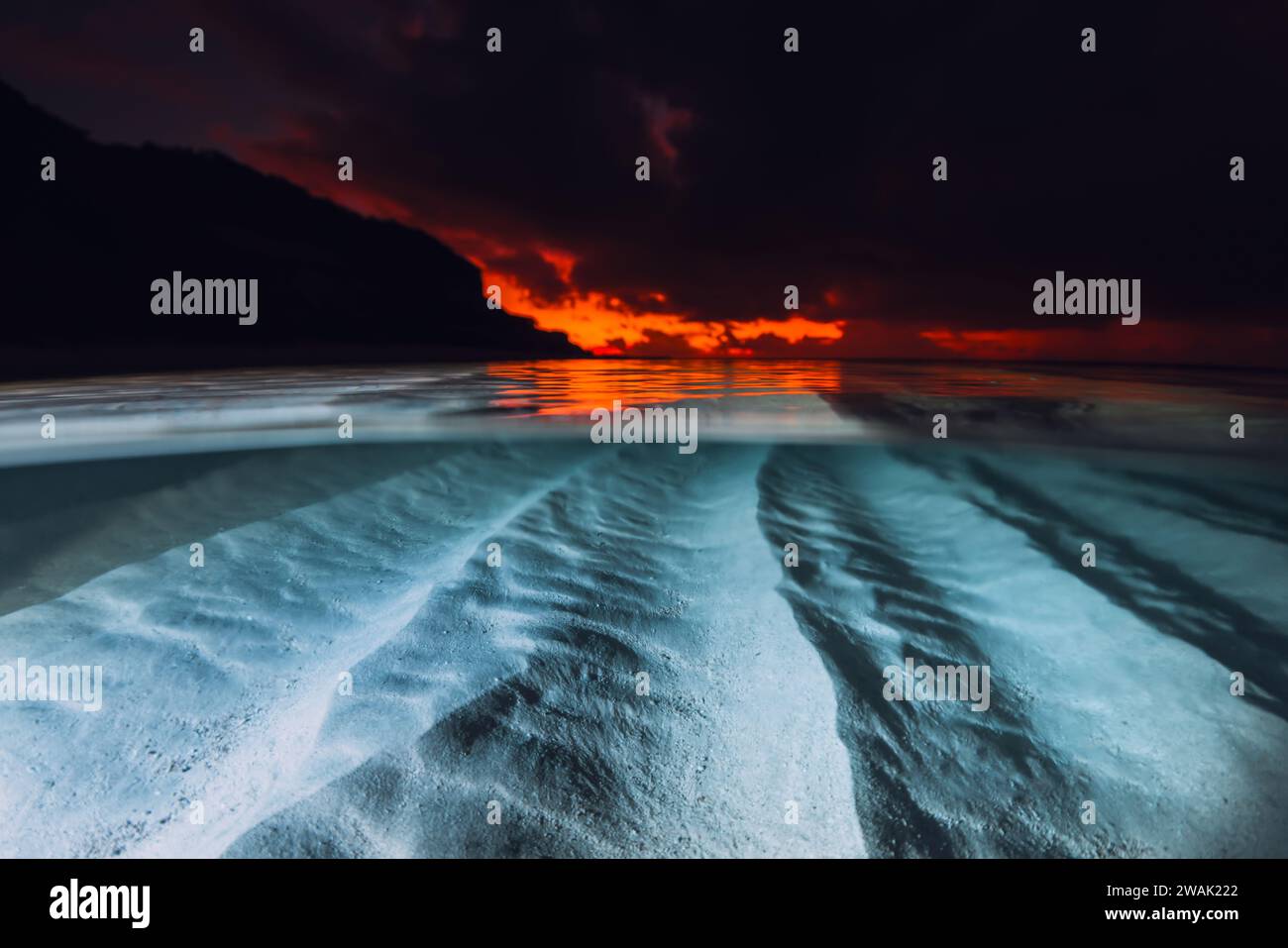 Vue partagée avec coucher ou lever du soleil et fond de mer sablonneux sous-marin. Mer tropicale avec coucher de soleil ou lever de soleil lumineux coloré, vue sous-marine avec flash lig Banque D'Images