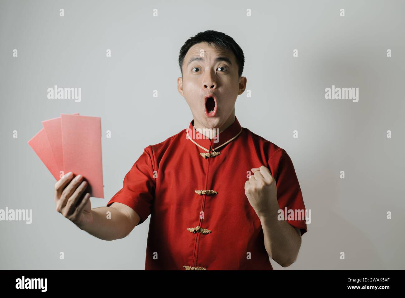 Visage heureux de l'homme asiatique portant Cheongsam ou tissu traditionnel chinois tout en tenant angpao sur fond blanc. Gong Xi Fa Cai. Banque D'Images