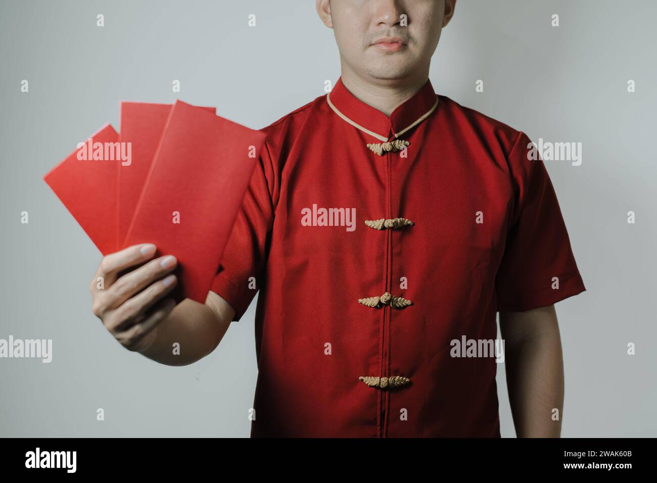 Homme asiatique portant Cheongsam ou tissu traditionnel chinois tient angpao et le montre à la caméra sur fond blanc. Gong Xi Fa Cai. Banque D'Images