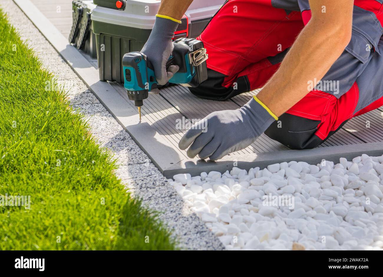 Travailleur avec une perceuse-visseuse dans ses mains installant la terrasse en matériau composite de la piscine Banque D'Images