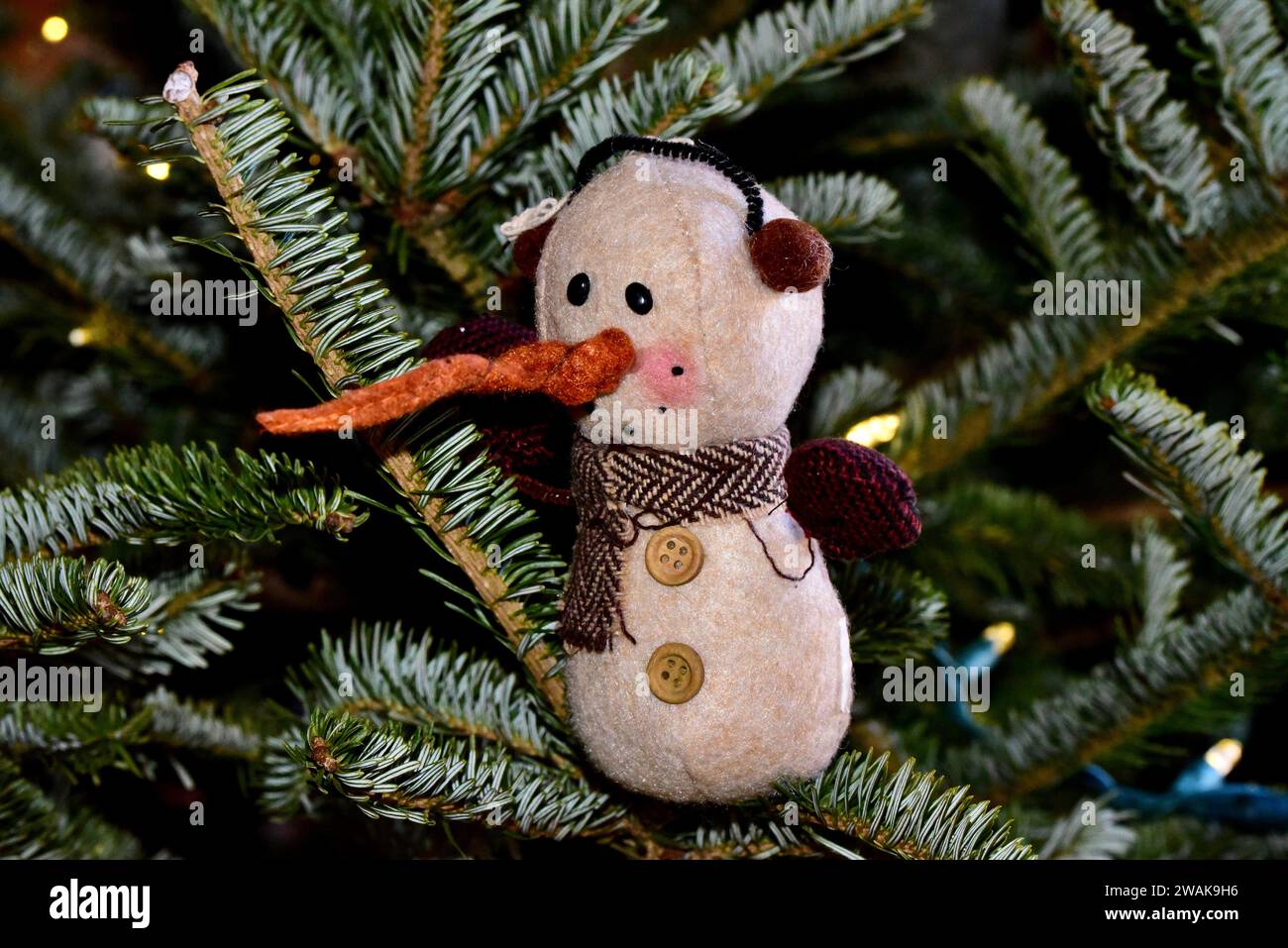 Un ornement de bonhomme de neige en feutre avec un long nez de carotte sur un arbre de Noël. Banque D'Images