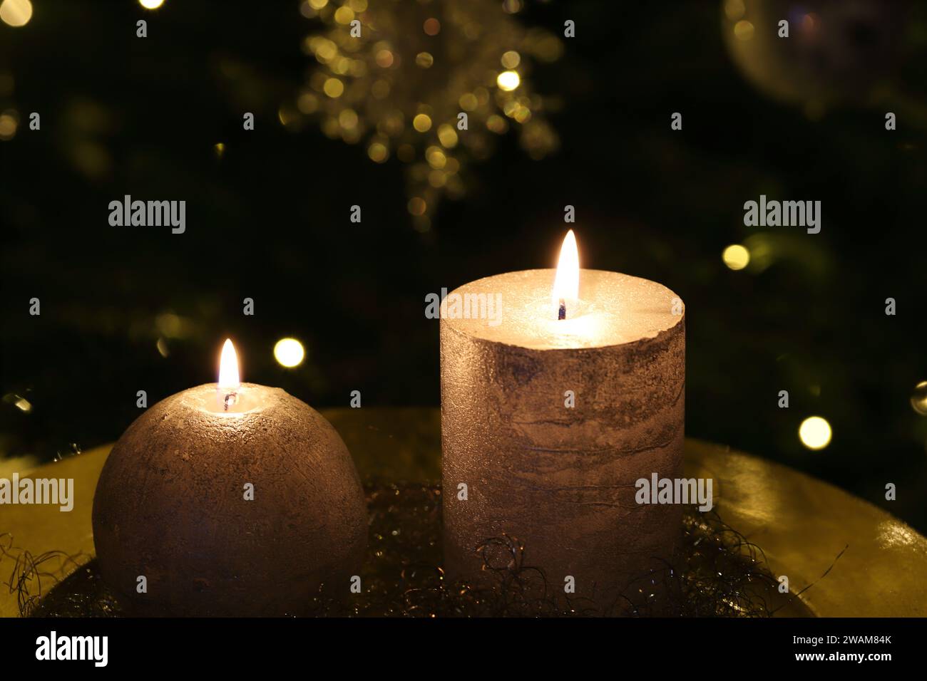 Gros plan de bougies allumées sur une plaque d'or, fond sombre de Noël, vue de côté, espace de copie Banque D'Images