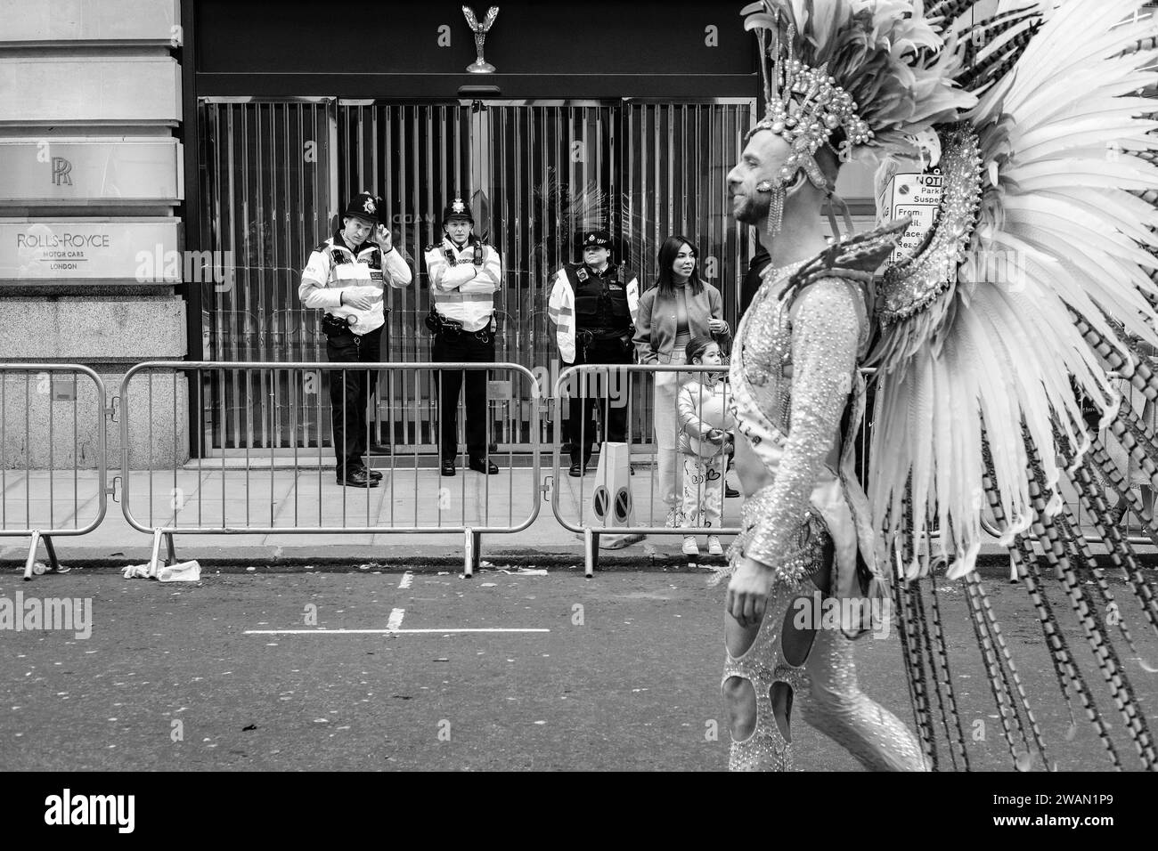 Les policiers regardent comme un interprète de la London School of Samba Pass au défilé du nouvel an de Londres 2024. Banque D'Images