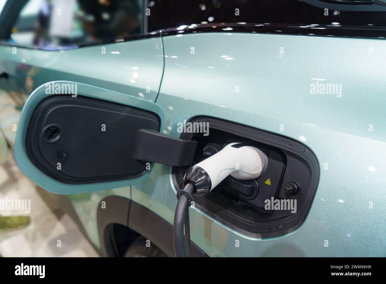 Voiture électrique au repos, connectée à une borne de recharge, incarnant l’avenir durable du transport urbain. Le câble d'alimentation relie parfaitement le véhicule Banque D'Images