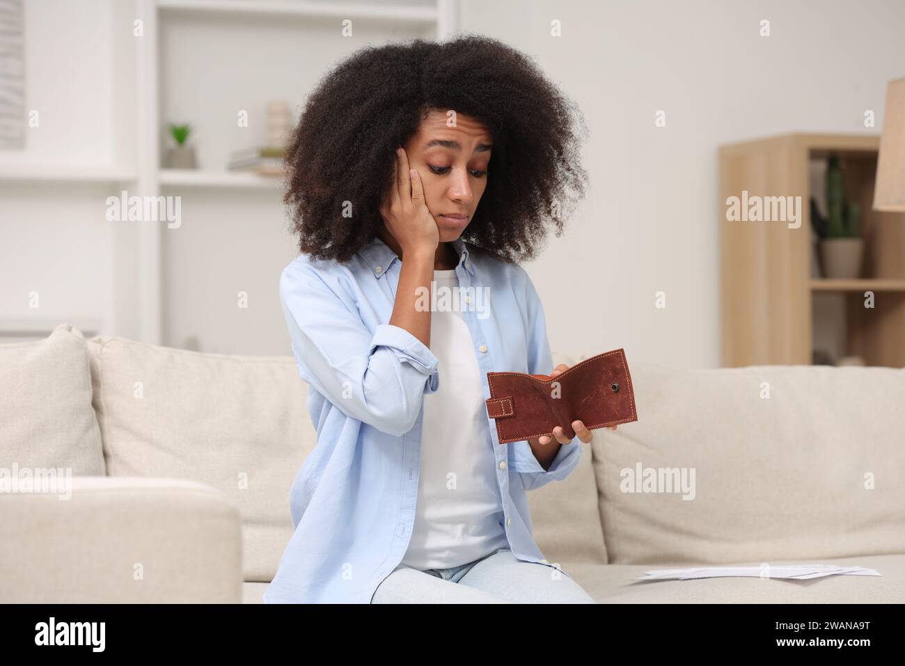 Femme choquée avec un portefeuille vide à la maison. Problème de dette Banque D'Images