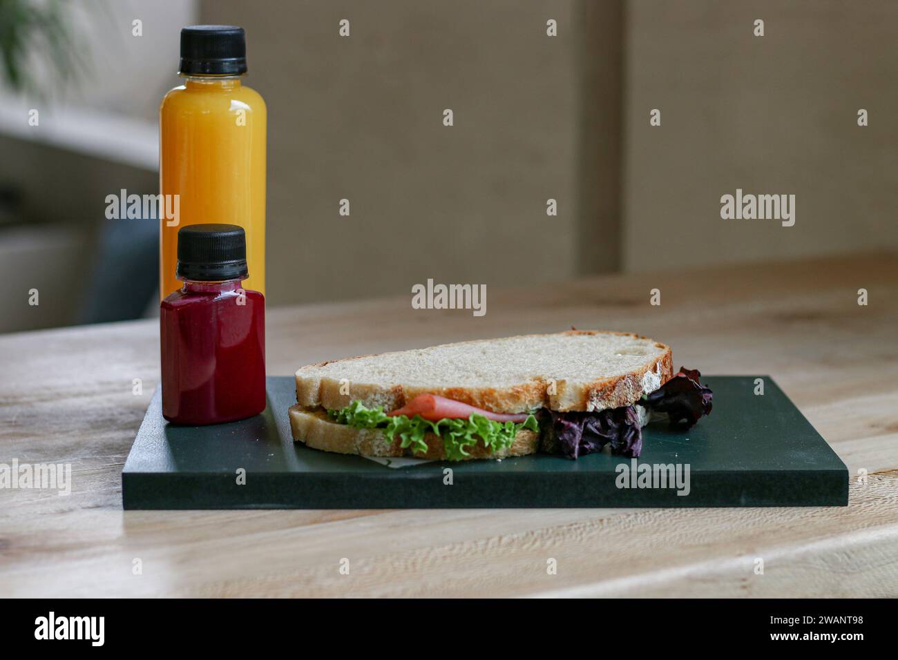 Hamburger avec laitue et fromage sur planche à découper en bois avec bouteille de jus sur la table Banque D'Images