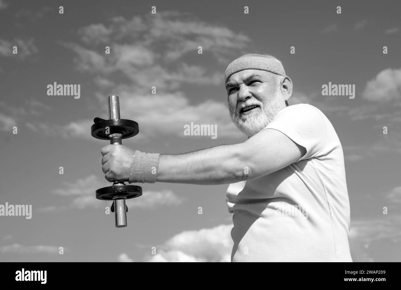 Portrait de grand-père sportif sur fond bleu ciel. Portrait d'un aîné en bonne santé. Homme senior dans ses années soixante-dix d'entraînement et de levage de poids. Banque D'Images