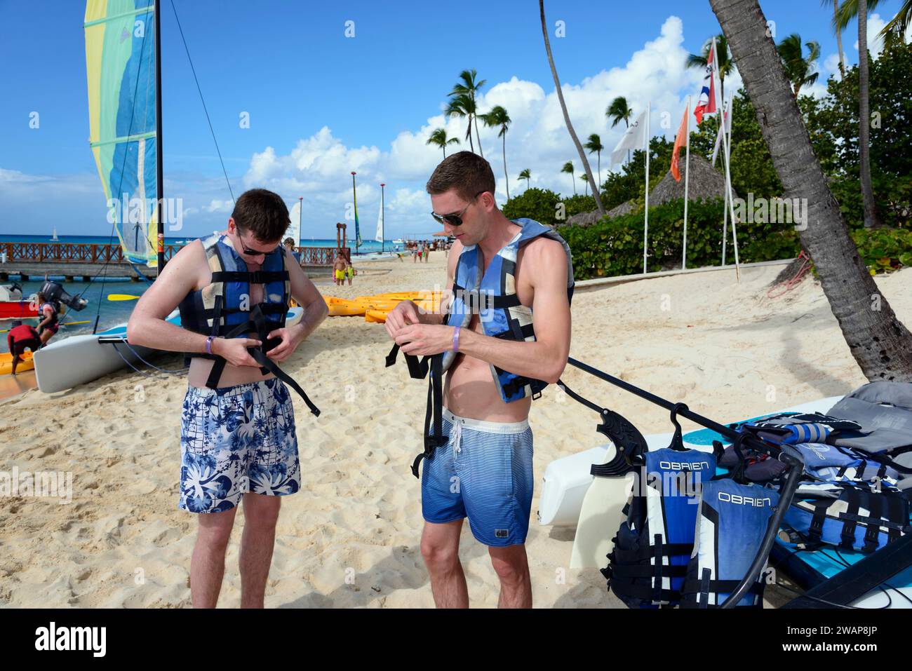 Deux hommes se préparent à naviguer sur la plage tropicale ensoleillée, voyage en catamaran, plage Dominicus, Bayahibe, République Dominicaine, Hispaniola, Caraïbes, Amérique, ce Banque D'Images