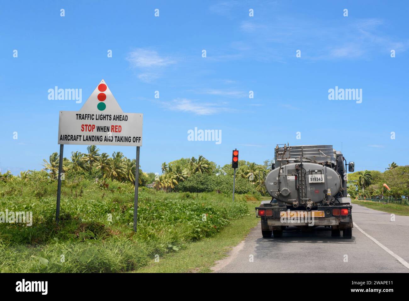 Les feux de circulation arrêtent les véhicules sur la route lorsque les avions à basse altitude arrivent et partent de l'aéroport sur l'île de Praslin, Seychelles, océan Indien Banque D'Images