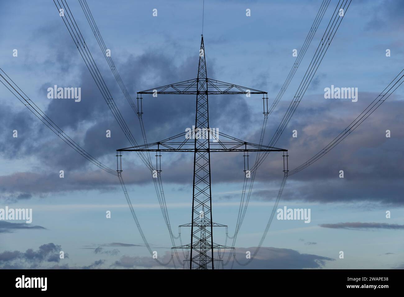 Photo minimaliste de pylônes à haute tension disposés géométriquement les uns derrière les autres avec une structure nuageuse intéressante. Banque D'Images