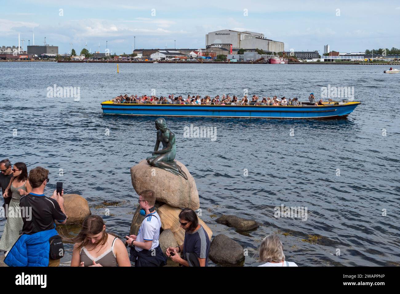 Bateau d'excursion passant près de la sculpture de la petite Sirène (Den Lille Havfrue) au bord de l'eau sur la promenade Langelinie, Copenhague, Danemark. Banque D'Images