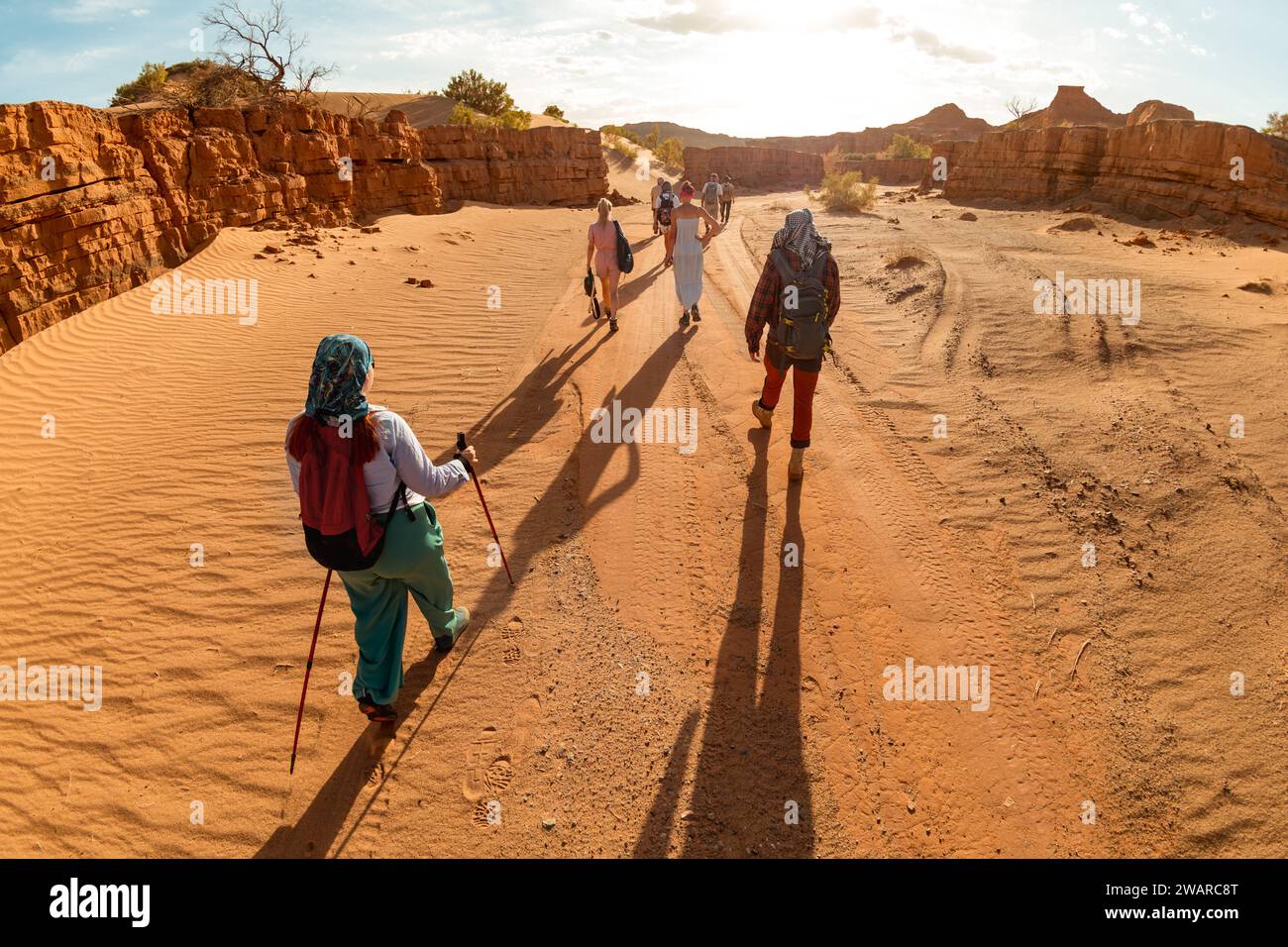 Grand groupe de randonneurs ou de touristes avec des sacs à dos promenades dans le désert au coucher du soleil. Désert de Gobi, Mongolie Banque D'Images