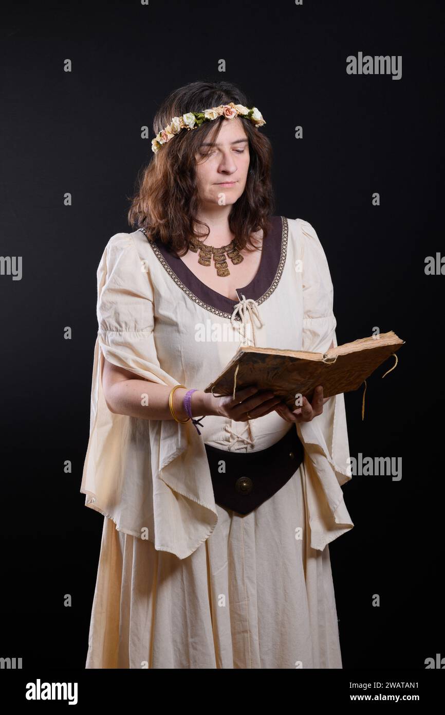 Portrait d'une belle femme vêtue de vêtements médiévaux, lisant un livre antique. Conte magique. Princesse médiévale. Banque D'Images